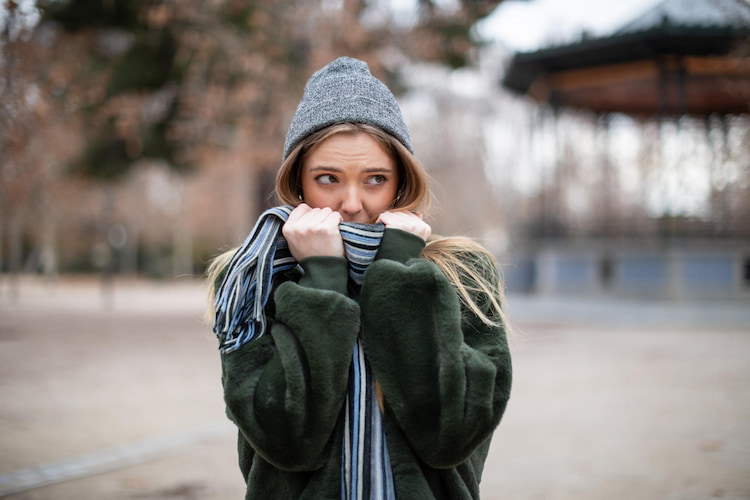 a woman covering face with scarf in outdoor during winter.