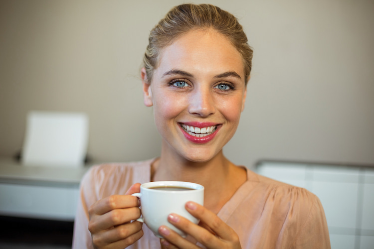a smiling woman holding a cup of coffee.