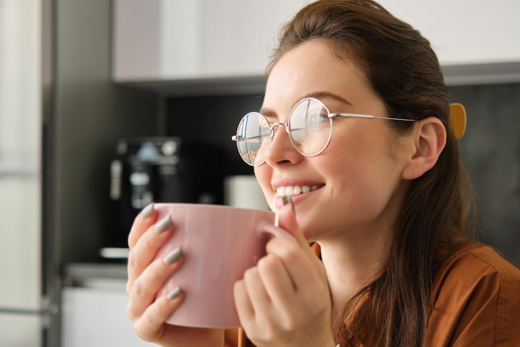 a girl is drinking a cup of coffee and smiling wondering about how to prevent cavities from coffee