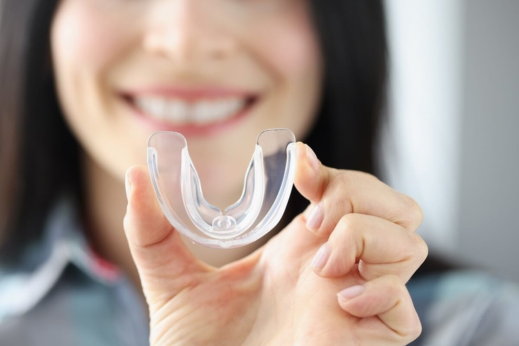 A close-up of a mouthguard held in the hands of a woman.