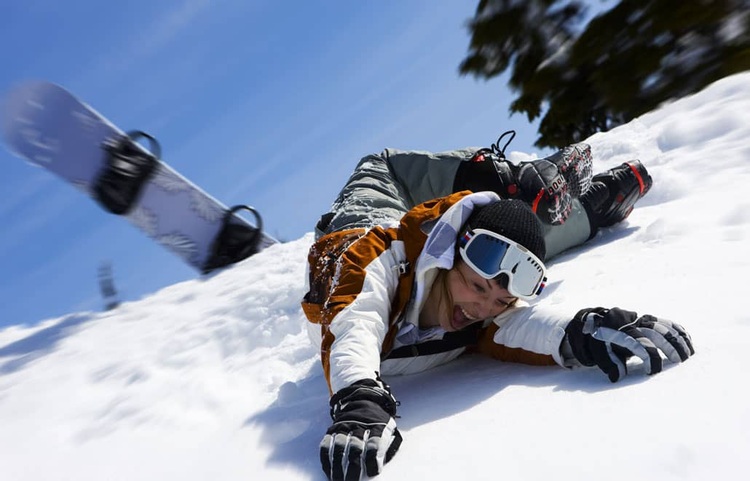 A female snowboarder sprawled on the snow after falling during snowboarding.