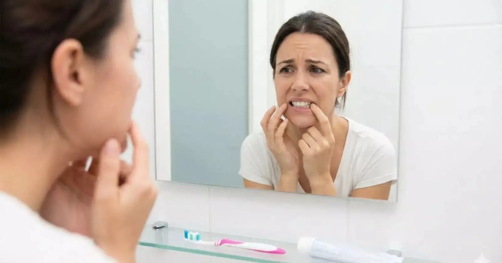 Young woman worriedly checking stained teeth in the mirror.
