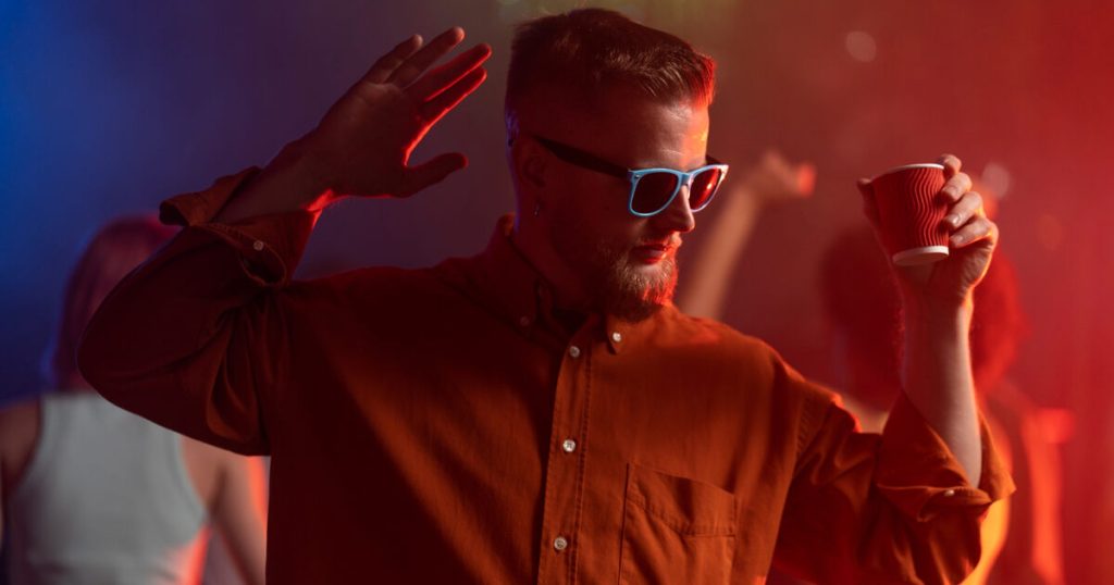 Young man dancing at a Toronto rave holding a drink after MDMA use