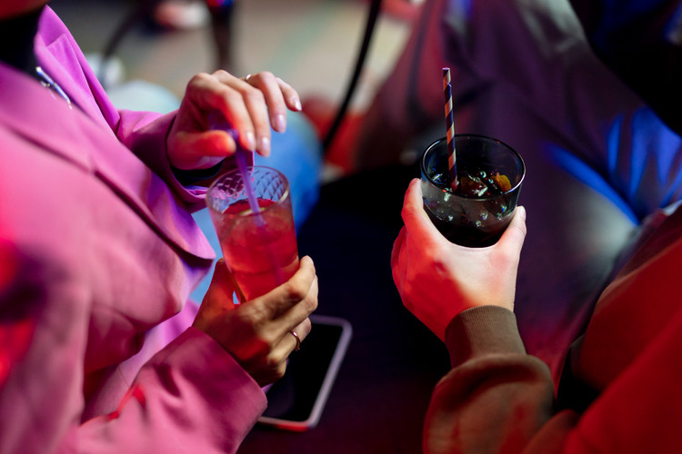Close-up of two drinks held by people at a Toronto nightclub rave at night