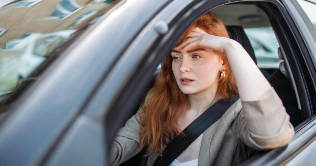 Stressed woman driving in Toronto traffic, clenching her teeth.
