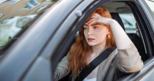 Stressed woman driving in Toronto traffic, clenching her teeth.