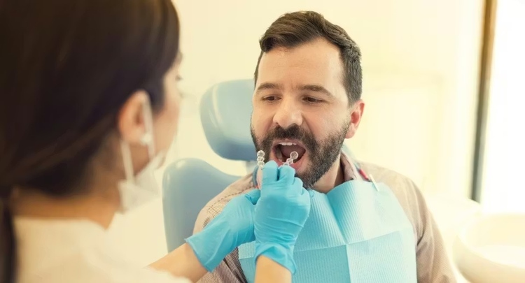 A female dentist placing a night guard on a male patient lying on a dental chair to help treat stress-related teeth grinding (bruxism).