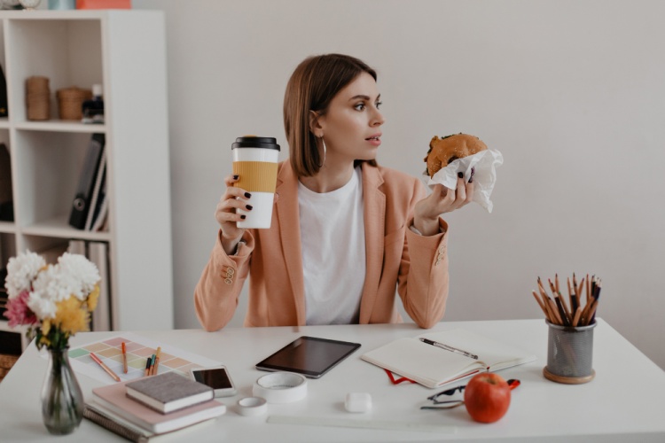 Young female teacher eating coffee and a donut in a classroom setting