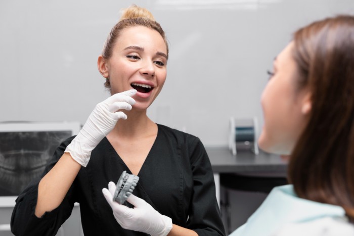 A female dentist explaining the various factors that affect the dental implants cost in Toronto to a patient.
