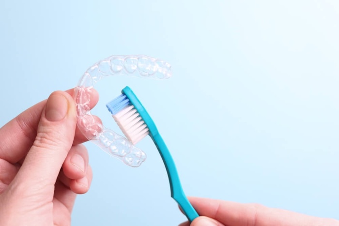 An Invisalign aligner and a toothbrush placed side by side.