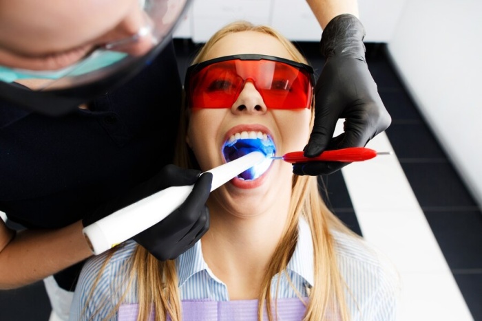 A woman receiving internal bleaching from a dentist to correct tooth discolouration after dead tooth treatment.