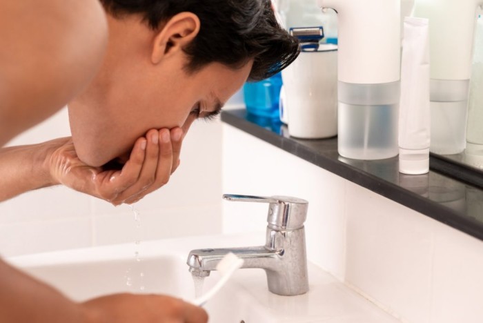 A young man rinsing his mouth out after his tooth filling fell out