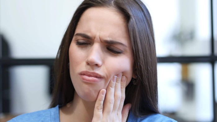 A young woman experiencing toothache after a tooth filling fell out