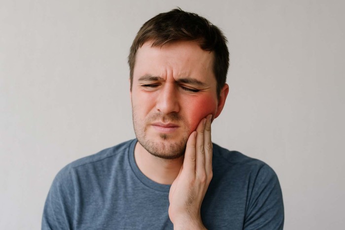 A man experiencing severe pain and swelling caused by an advanced gum boil infection.